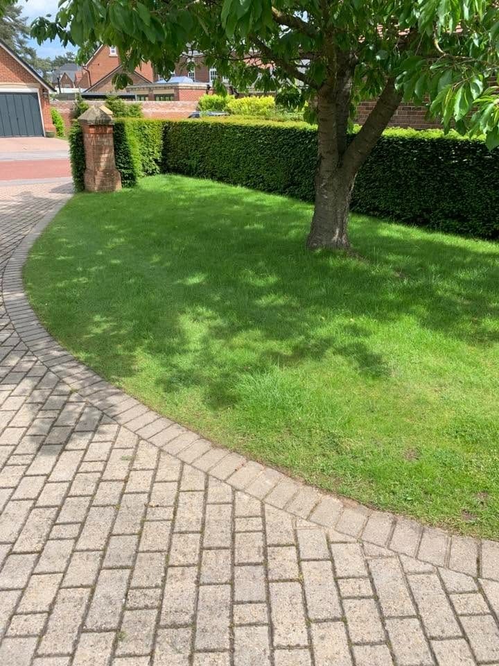 A curved block-paved path through the freshly cut front lawn